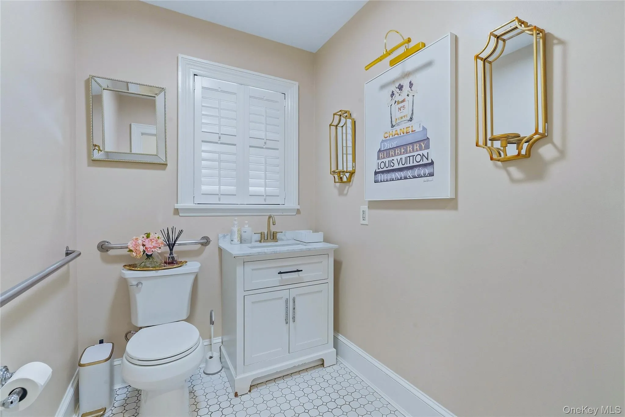 White shaker-style vanity with a solid surface countertop and gold-tone faucet White shaker-style vanity with a solid surface countertop and gold-tone faucet