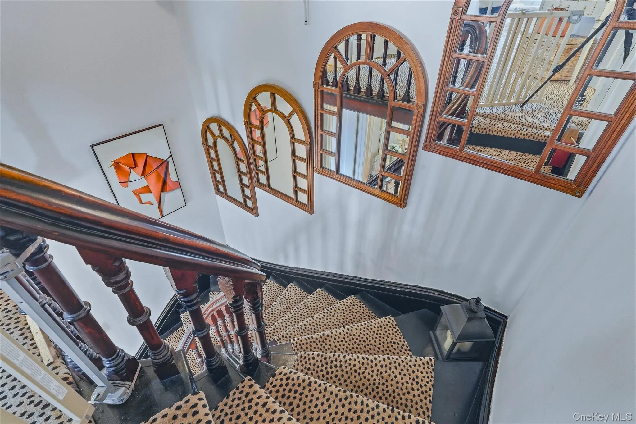 Staircase featuring dark wood banister and balusters, painted risers, and decorative wall mirrors Staircase featuring dark wood banister and balusters, painted risers, and decorative wall mirrors