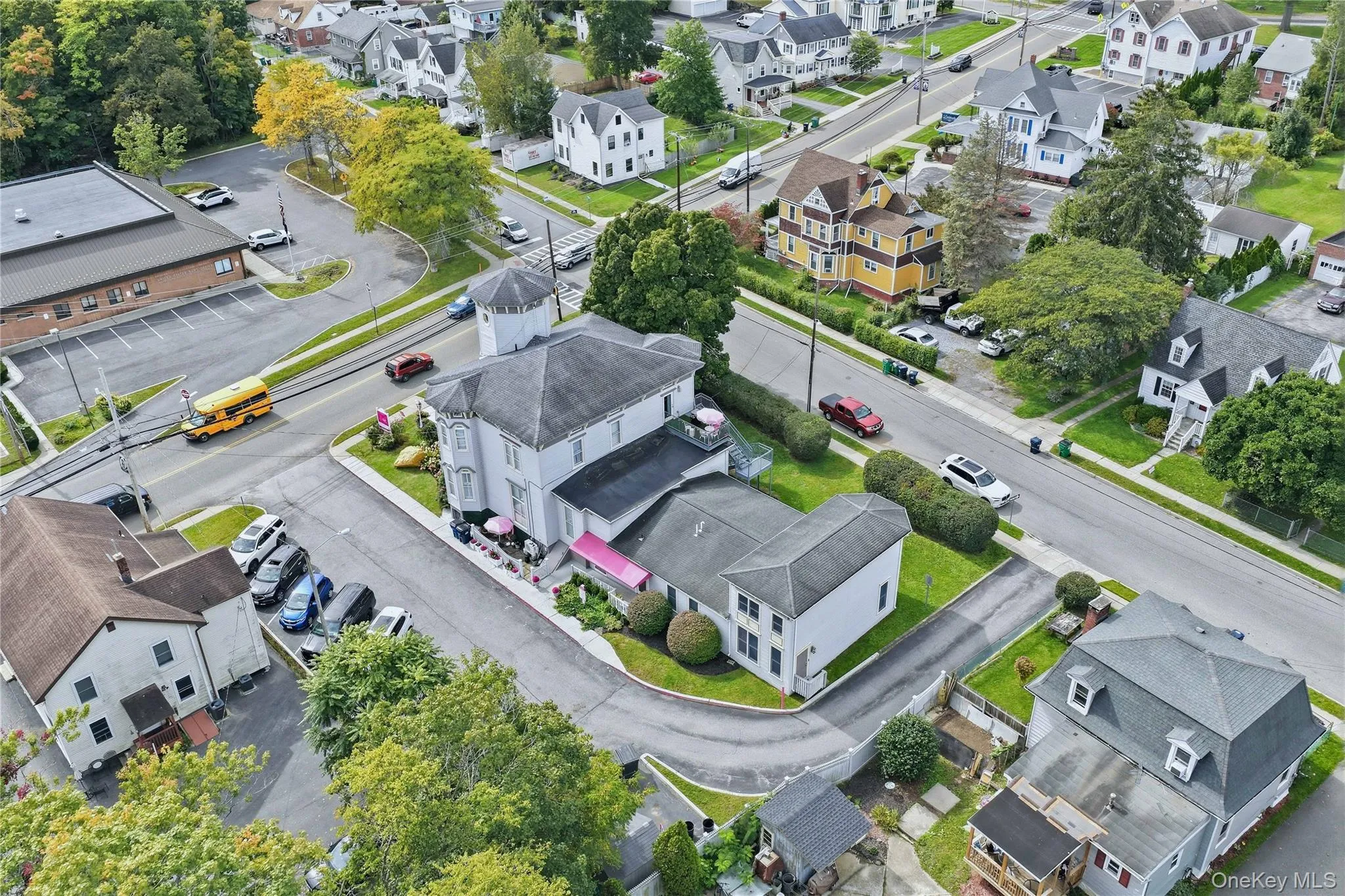 Multi-level building with a turret, multiple street-facing entrances, and a paved parking area Multi-level building with a turret, multiple street-facing entrances, and a paved parking area