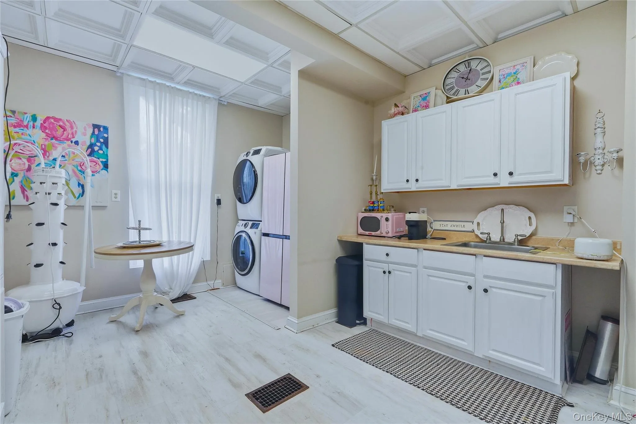 White wood-finish flooring, white cabinetry, integrated sink, and patterned ceiling panels White wood-finish flooring, white cabinetry, integrated sink, and patterned ceiling panels