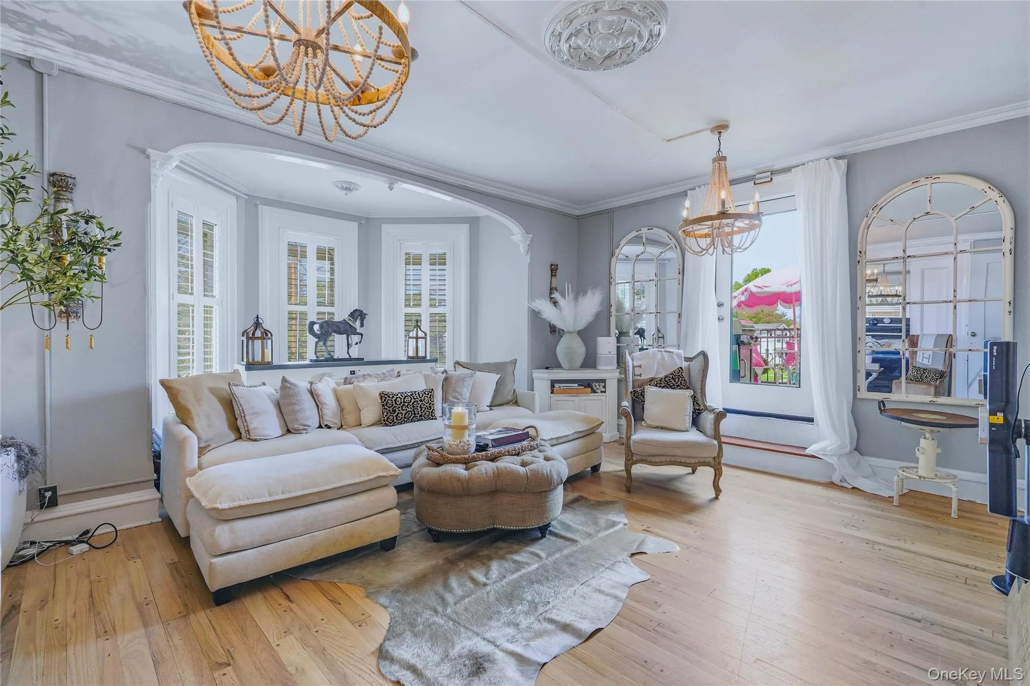 Wood-finish flooring throughout, bay window with plantation shutters, decorative ceiling medallions, and a decorative beaded chandelier Wood-finish flooring throughout, bay window with plantation shutters, decorative ceiling medallions, and a decorative beaded chandelier