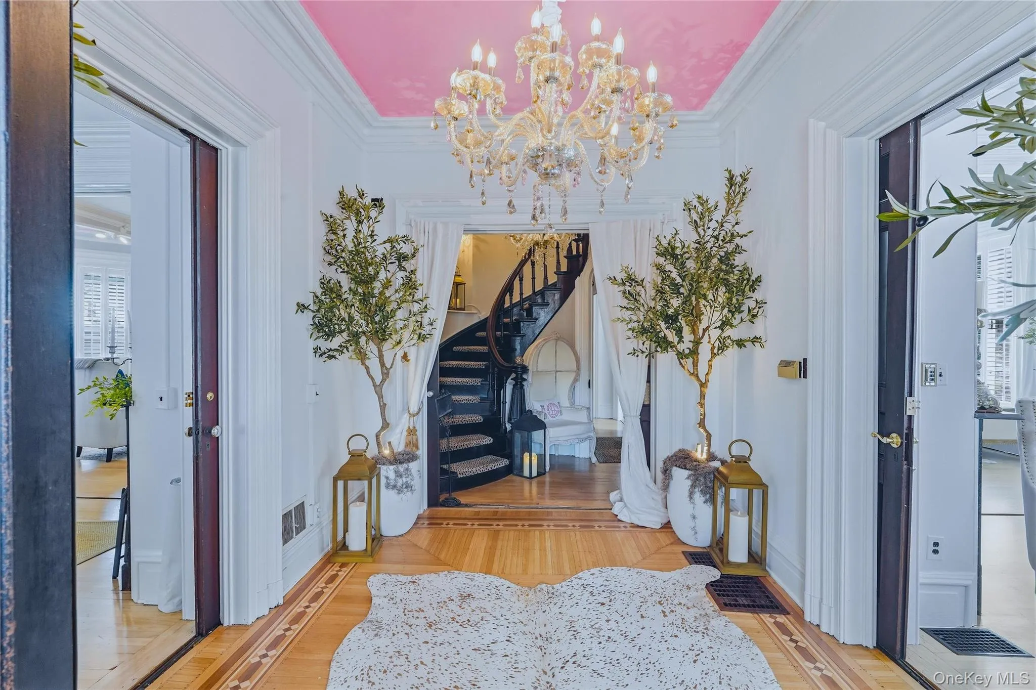 Foyer featuring a large chandelier, wood-finish flooring with inlay details, and a visible spiral staircase Foyer featuring a large chandelier, wood-finish flooring with inlay details, and a visible spiral staircase
