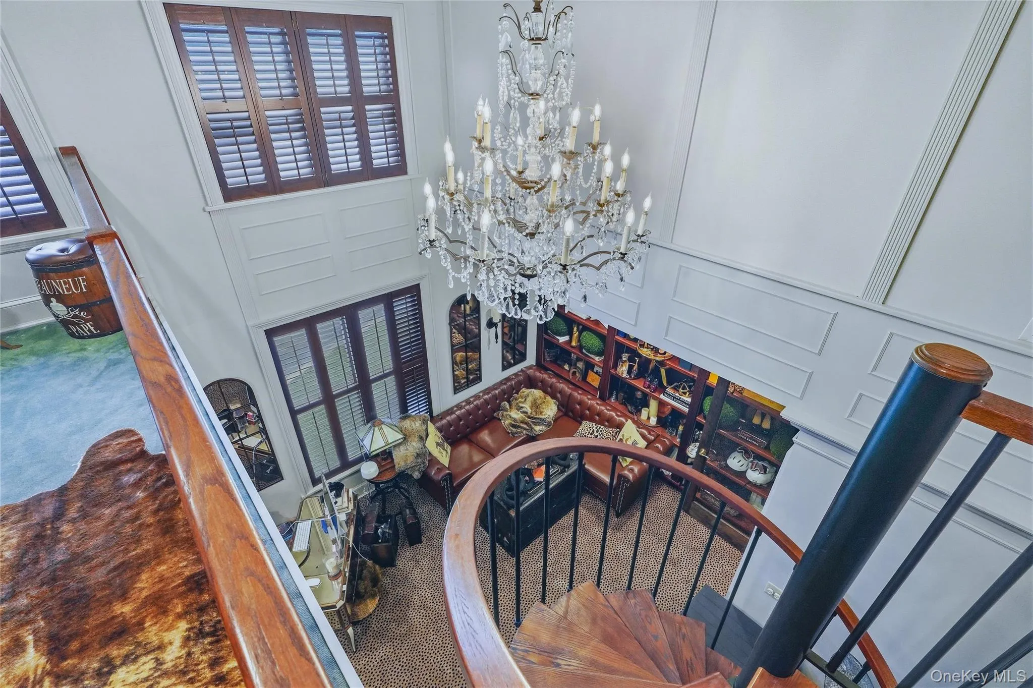Two-story living space with a spiral staircase, a crystal chandelier, and built-in shelving Two-story living space with a spiral staircase, a crystal chandelier, and built-in shelving