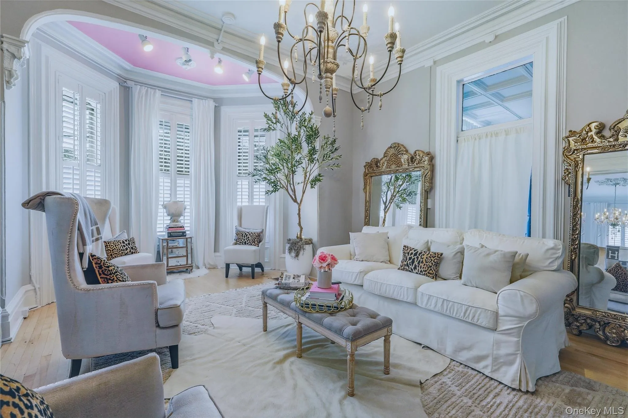 Hardwood flooring, bay window with plantation shutters, coffered ceiling, ornate chandelier, and decorative wall mirrors Hardwood flooring, bay window with plantation shutters, coffered ceiling, ornate chandelier, and decorative wall mirrors