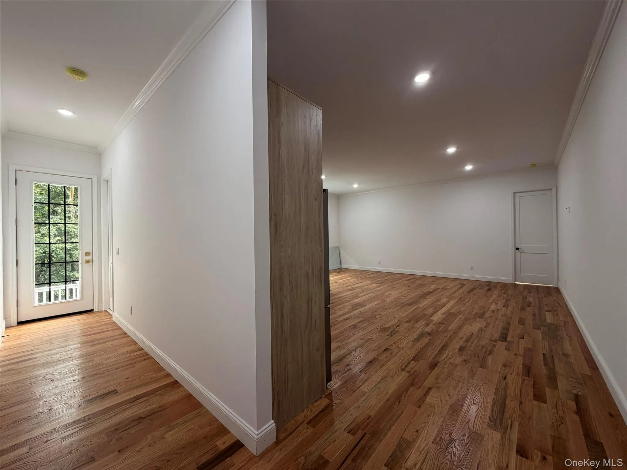 Hardwood flooring, recessed ceiling lighting, crown molding, white painted walls, and a glass-paneled entry door Hardwood flooring, recessed ceiling lighting, crown molding, white painted walls, and a glass-paneled entry door