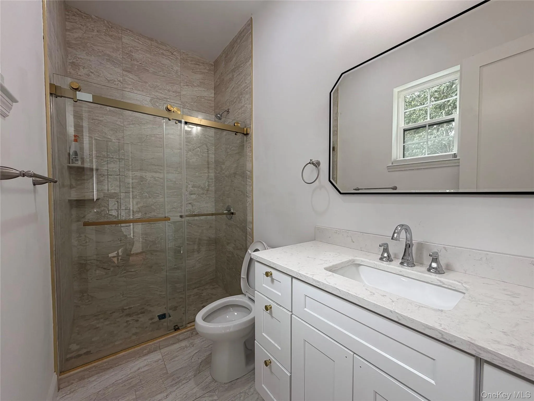 Walk-in shower with full-height tile surround and gold-finish sliding glass door Walk-in shower with full-height tile surround and gold-finish sliding glass door