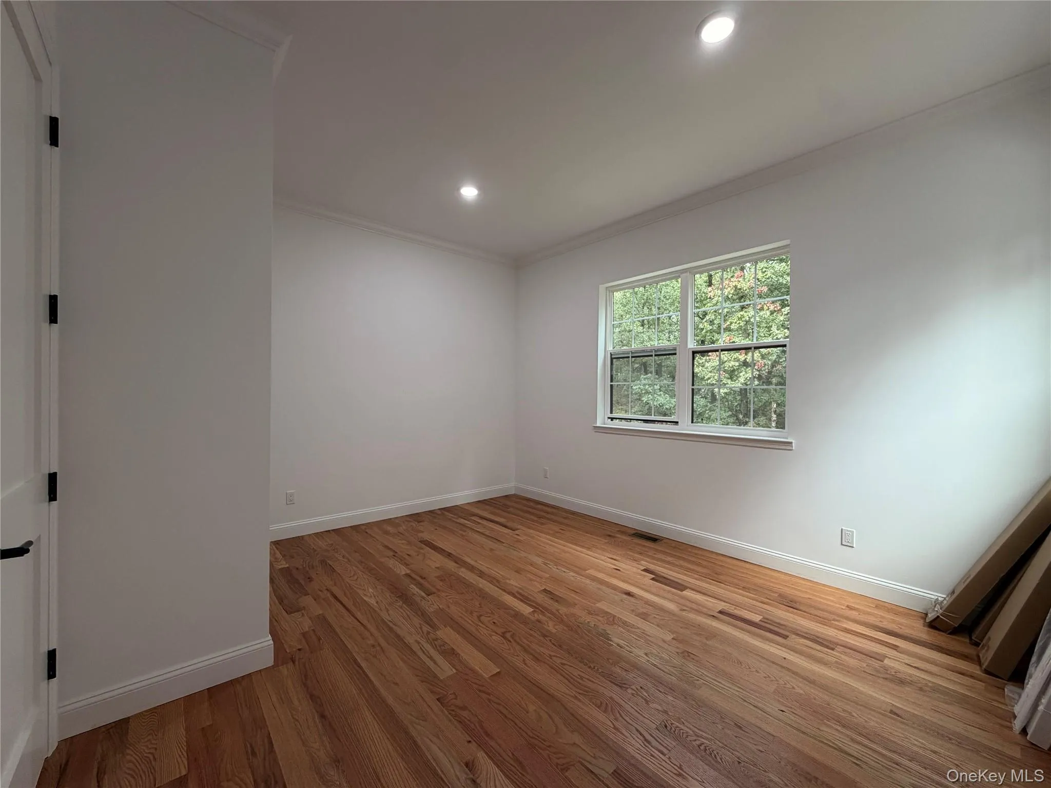 Hardwood flooring, recessed lighting, crown molding, white trim, and a double-hung window Hardwood flooring, recessed lighting, crown molding, white trim, and a double-hung window
