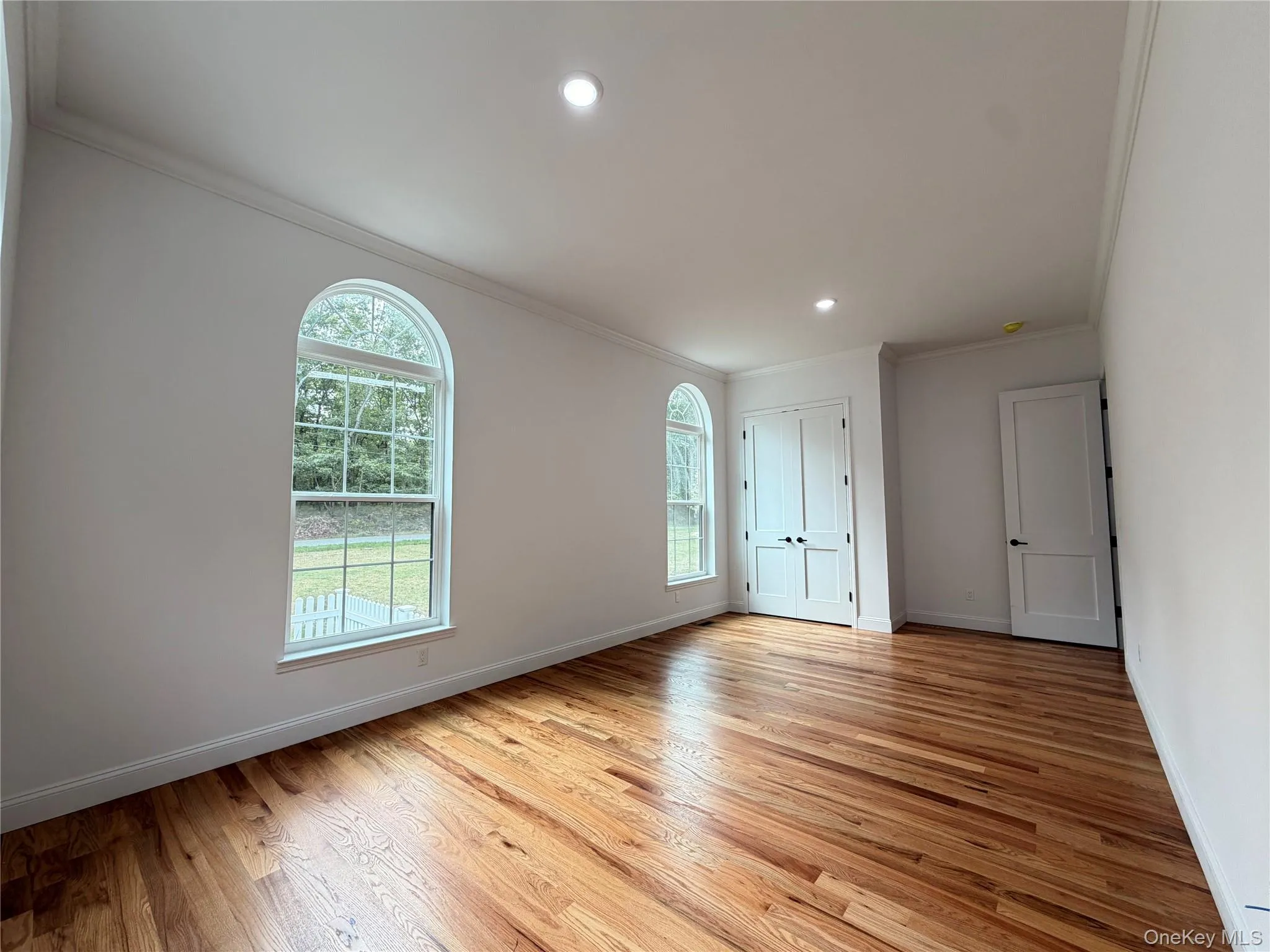 Hardwood flooring, arched windows, recessed lighting, crown molding, and a paneled double-door closet Hardwood flooring, arched windows, recessed lighting, crown molding, and a paneled double-door closet
