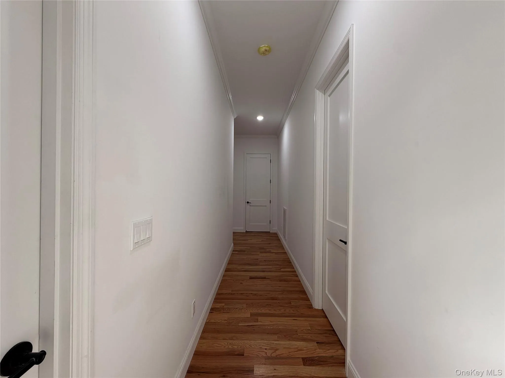 Hallway with wood-finish flooring, recessed lighting, and white doors Hallway with wood-finish flooring, recessed lighting, and white doors
