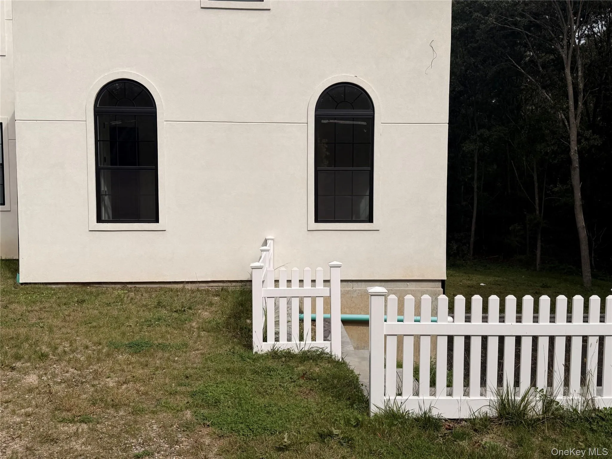 Stucco exterior featuring arched windows and a white picket fence Stucco exterior featuring arched windows and a white picket fence