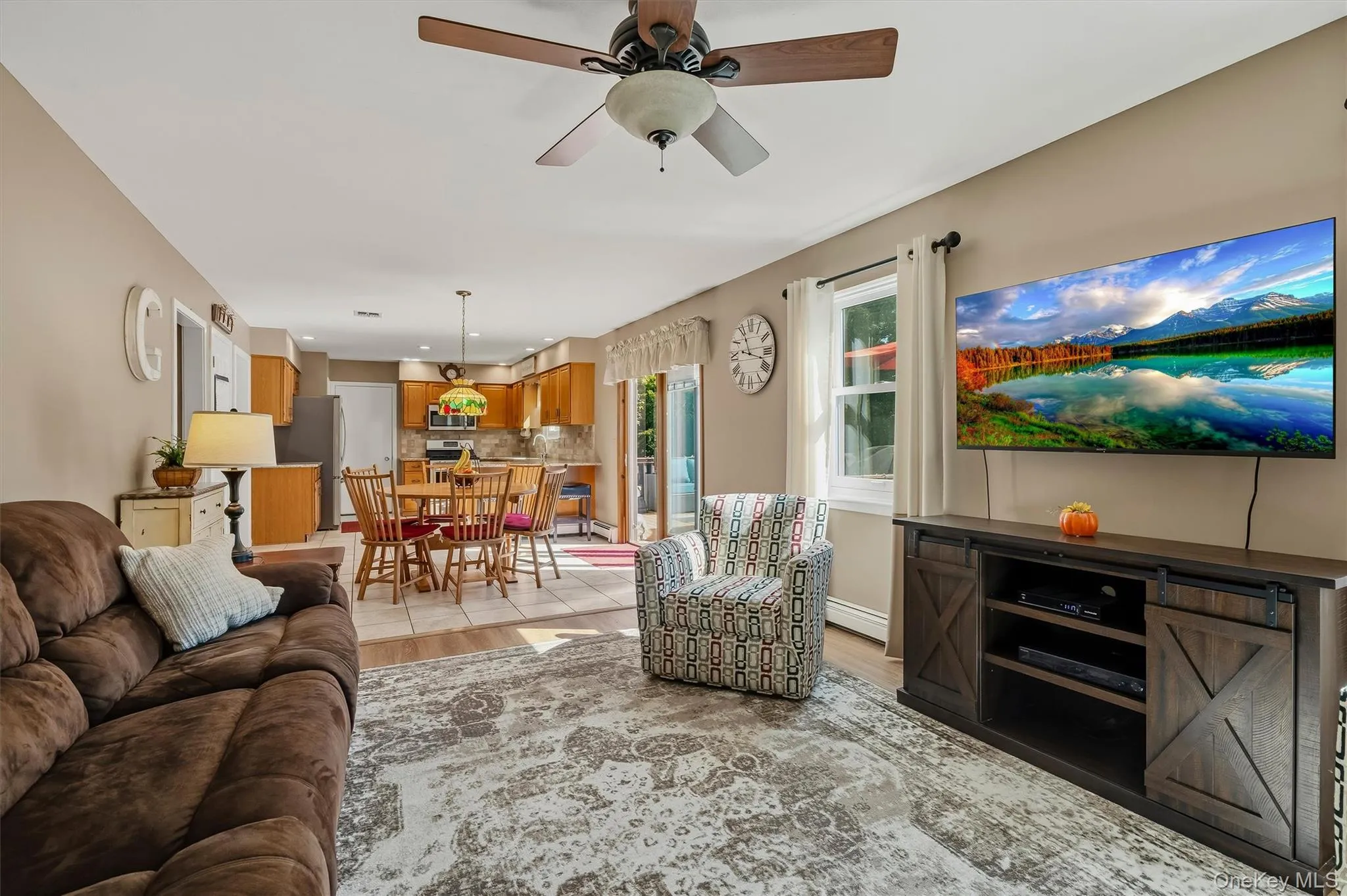 Open-concept living space featuring a ceiling fan, wall-mounted television, and wood-finish media console Open-concept living space featuring a ceiling fan, wall-mounted television, and wood-finish media console