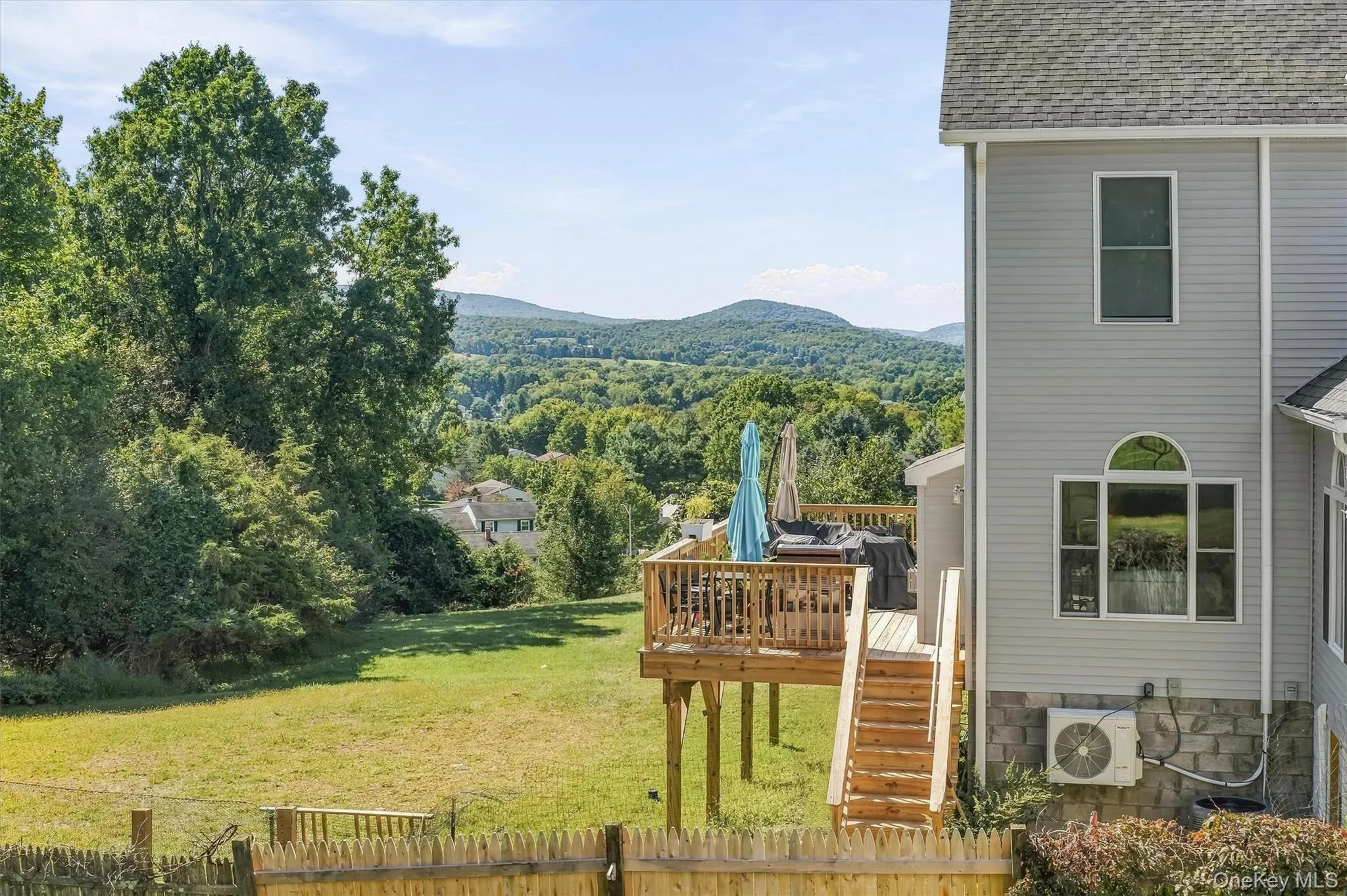 Expansive backyard with a wooden fence, large wooden deck, and mountain scenery Expansive backyard with a wooden fence, large wooden deck, and mountain scenery