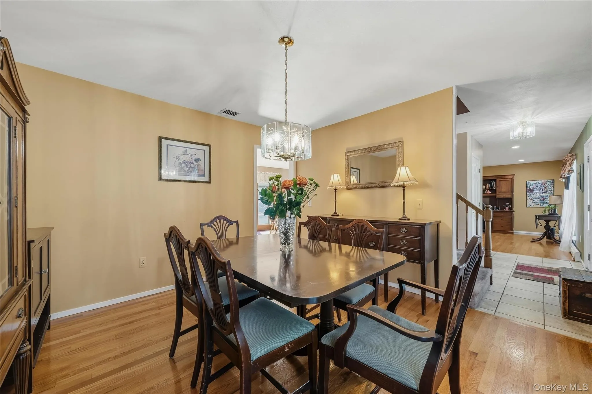 Hardwood flooring, chandelier lighting, built-in cabinetry, and a staircase with a wooden handrail Hardwood flooring, chandelier lighting, built-in cabinetry, and a staircase with a wooden handrail