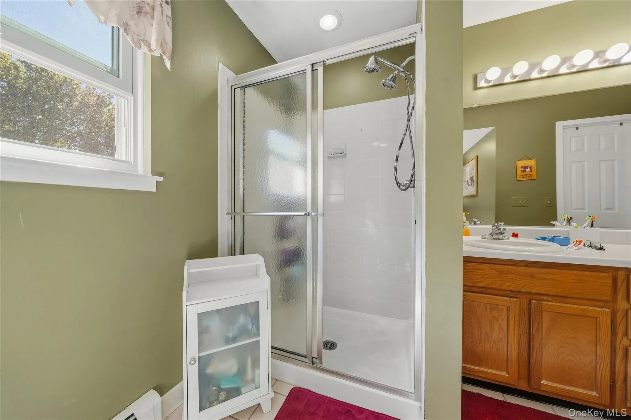 Shower enclosure with sliding glass door, white shower surround, and dual shower heads Shower enclosure with sliding glass door, white shower surround, and dual shower heads
