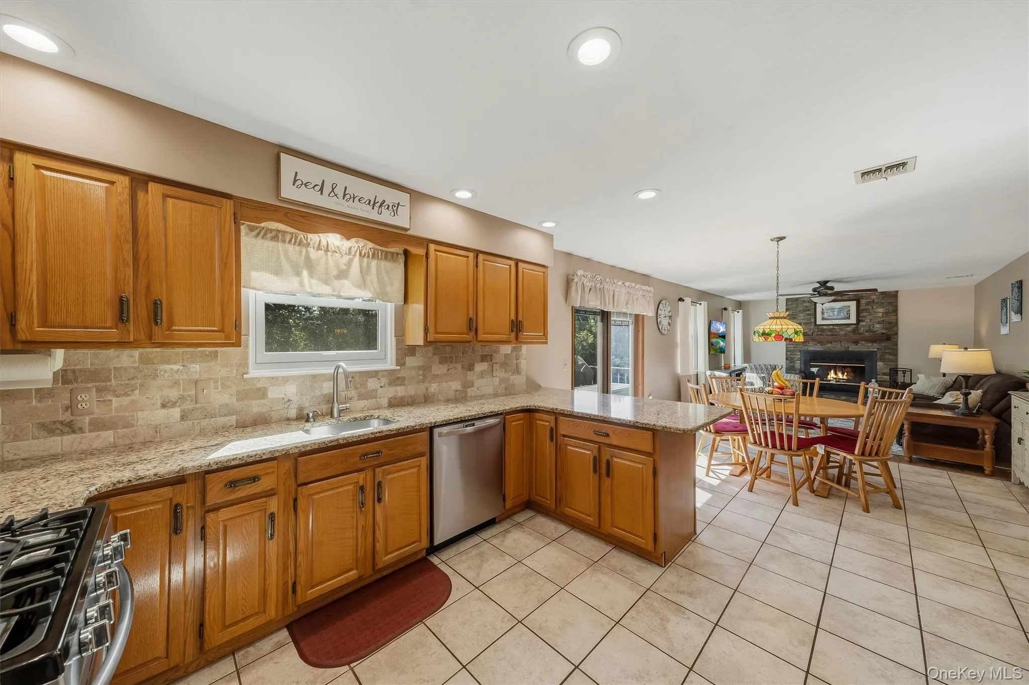 Kitchen featuring wood cabinetry, light-toned stone countertops, and a tiled backsplash Kitchen featuring wood cabinetry, light-toned stone countertops, and a tiled backsplash