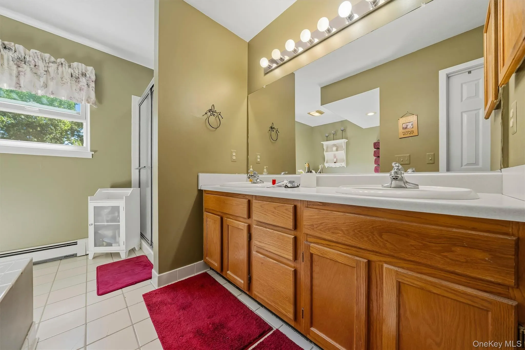 Dual vanity with wood-finish cabinetry, integrated sinks, and a full-width mirror Dual vanity with wood-finish cabinetry, integrated sinks, and a full-width mirror