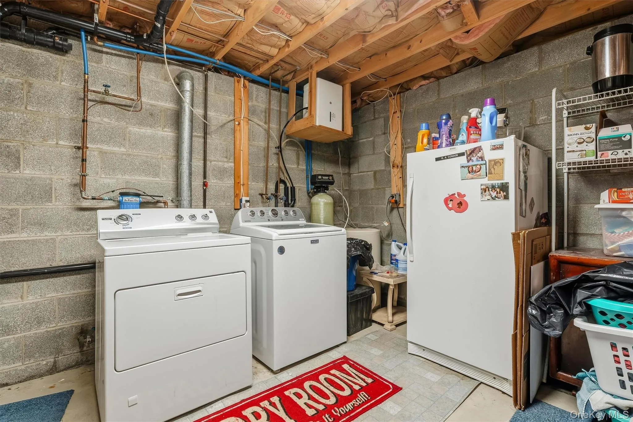 Dedicated utility area featuring a washer and dryer set, exposed ceiling joists, concrete block walls, and visible plumbing Dedicated utility area featuring a washer and dryer set, exposed ceiling joists, concrete block walls, and visible plumbing