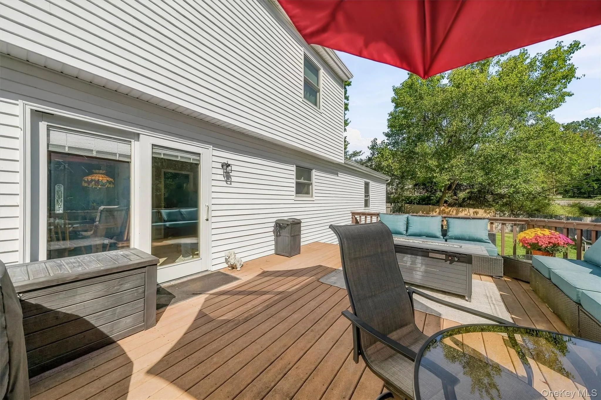 Expansive wood-finish deck with white siding exterior and sliding glass door Expansive wood-finish deck with white siding exterior and sliding glass door