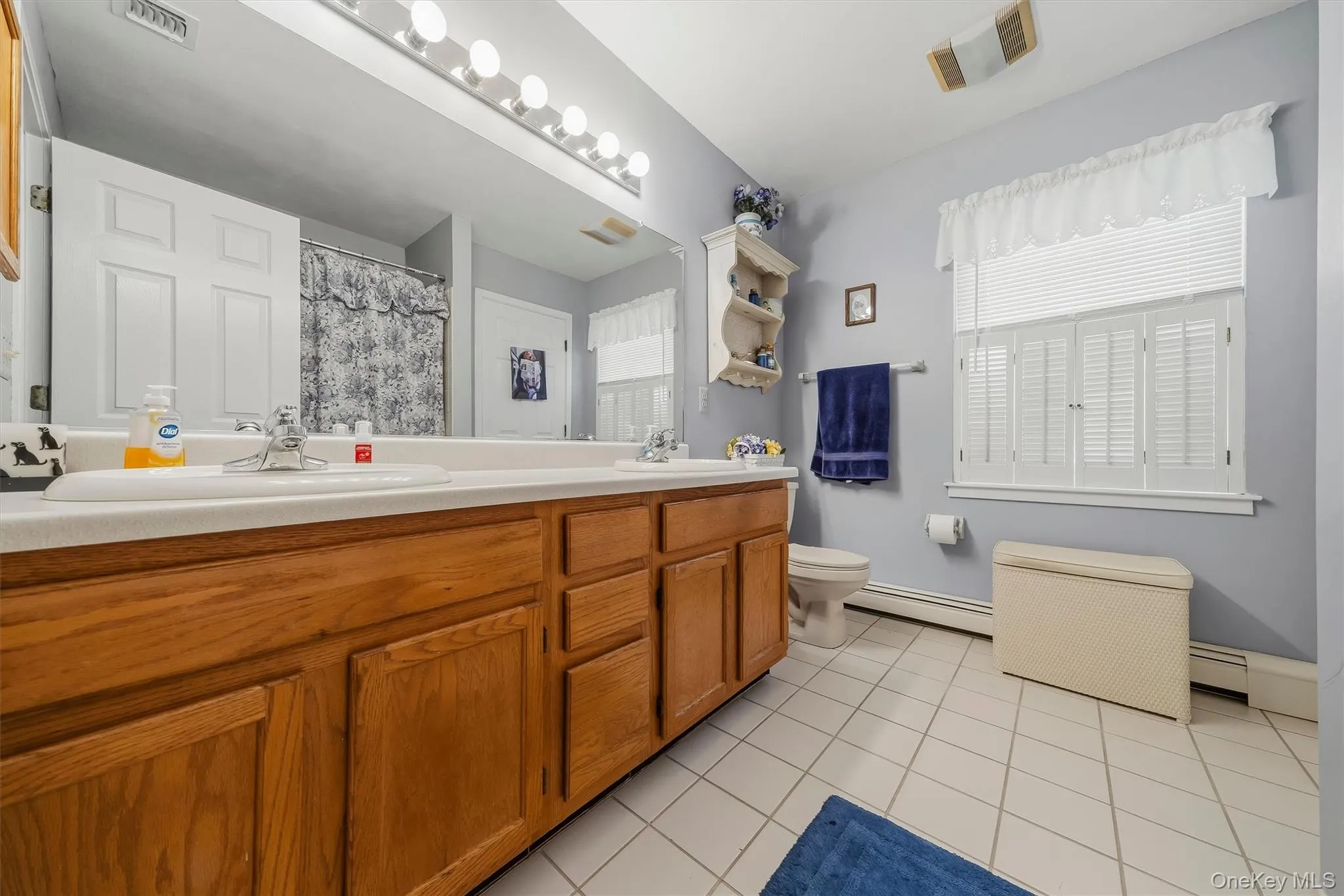 Double vanity with wood-finish cabinetry, dual sinks, and an expansive mirror Double vanity with wood-finish cabinetry, dual sinks, and an expansive mirror