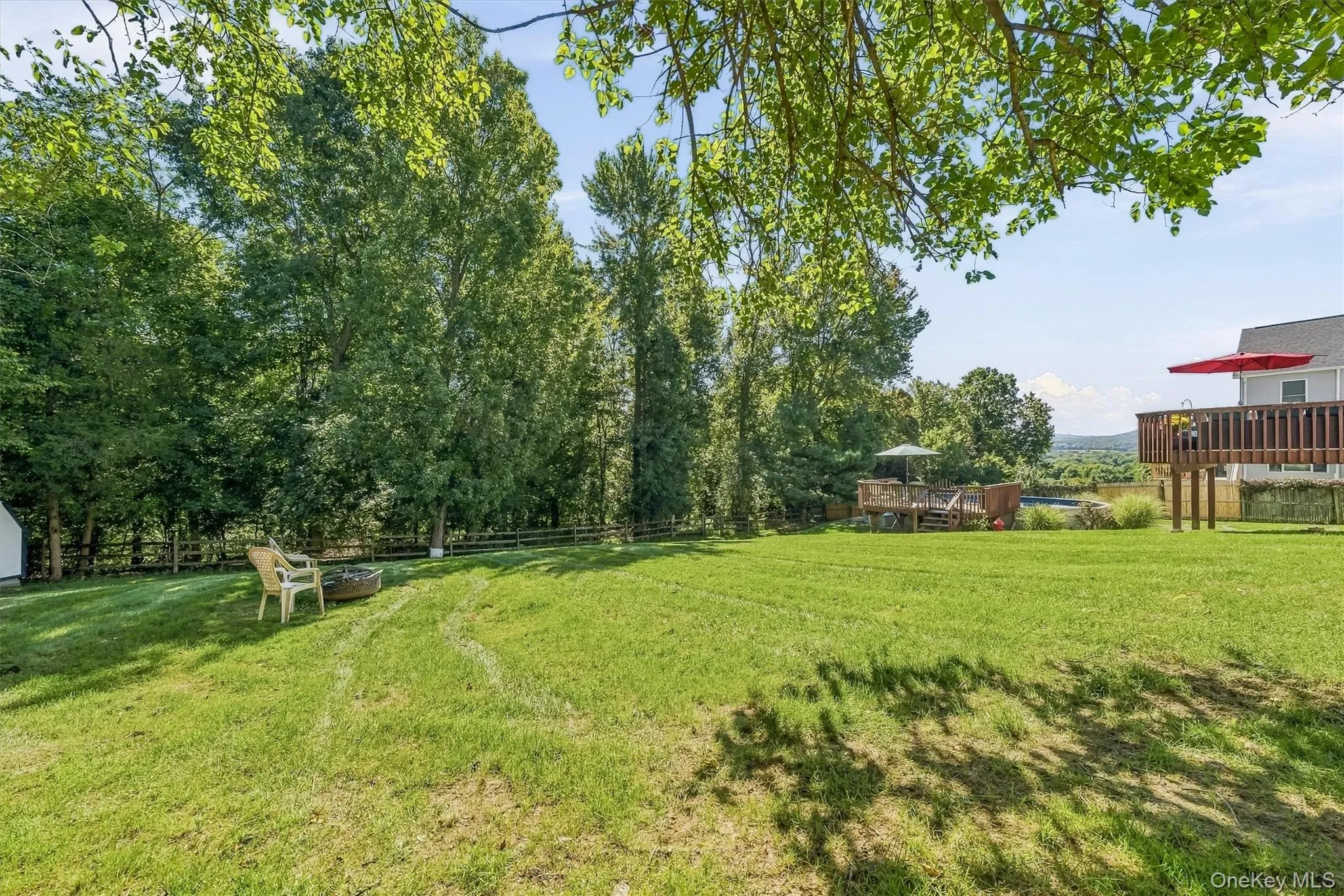 Expansive lawn area with mature trees, a fire pit, and a multi-level wooden deck Expansive lawn area with mature trees, a fire pit, and a multi-level wooden deck