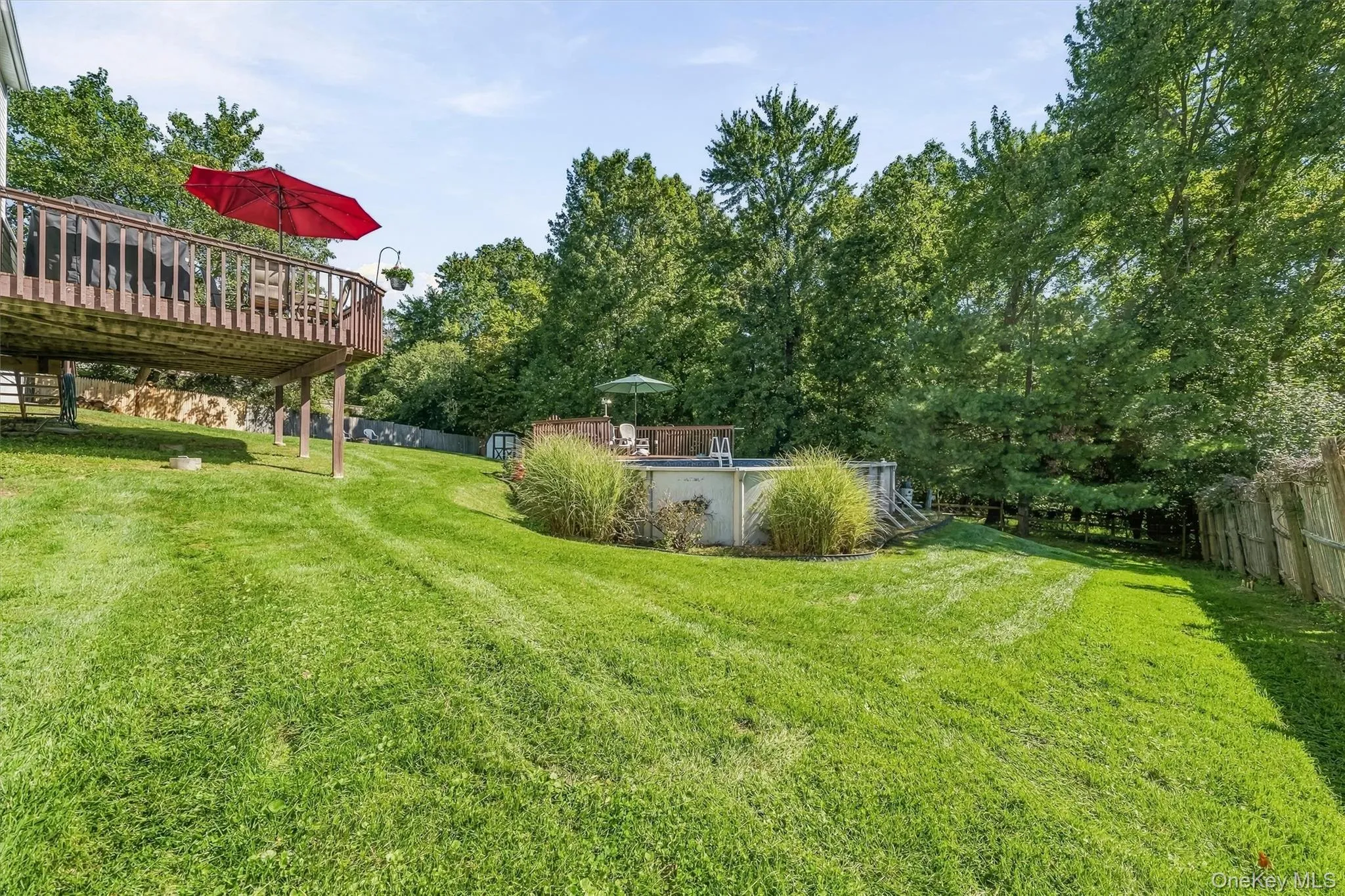 Elevated wood deck, expansive green lawn, above-ground pool, pool deck, and mature trees Elevated wood deck, expansive green lawn, above-ground pool, pool deck, and mature trees
