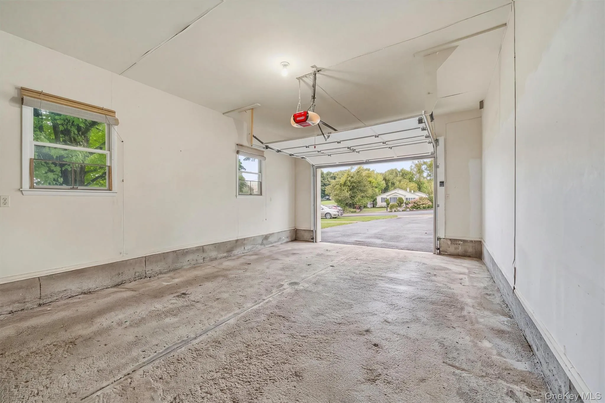 Attached garage space with a concrete floor, two windows, and an overhead door Attached garage space with a concrete floor, two windows, and an overhead door
