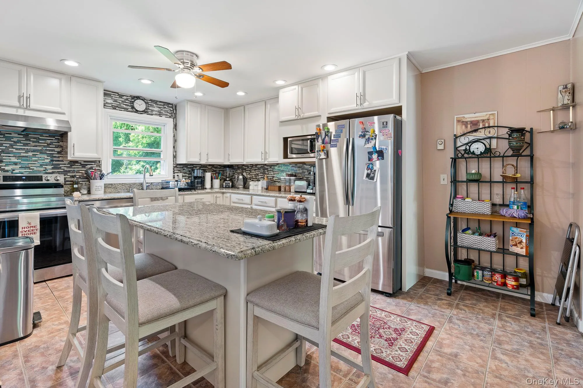 Kitchen featuring appliances with stainless steel finishes, under cabinet range hood, ceiling fan, tasteful backsplash, and a breakfast bar area Kitchen featuring appliances with stainless steel finishes, under cabinet range hood, ceiling fan, tasteful backsplash, and a breakfast bar area