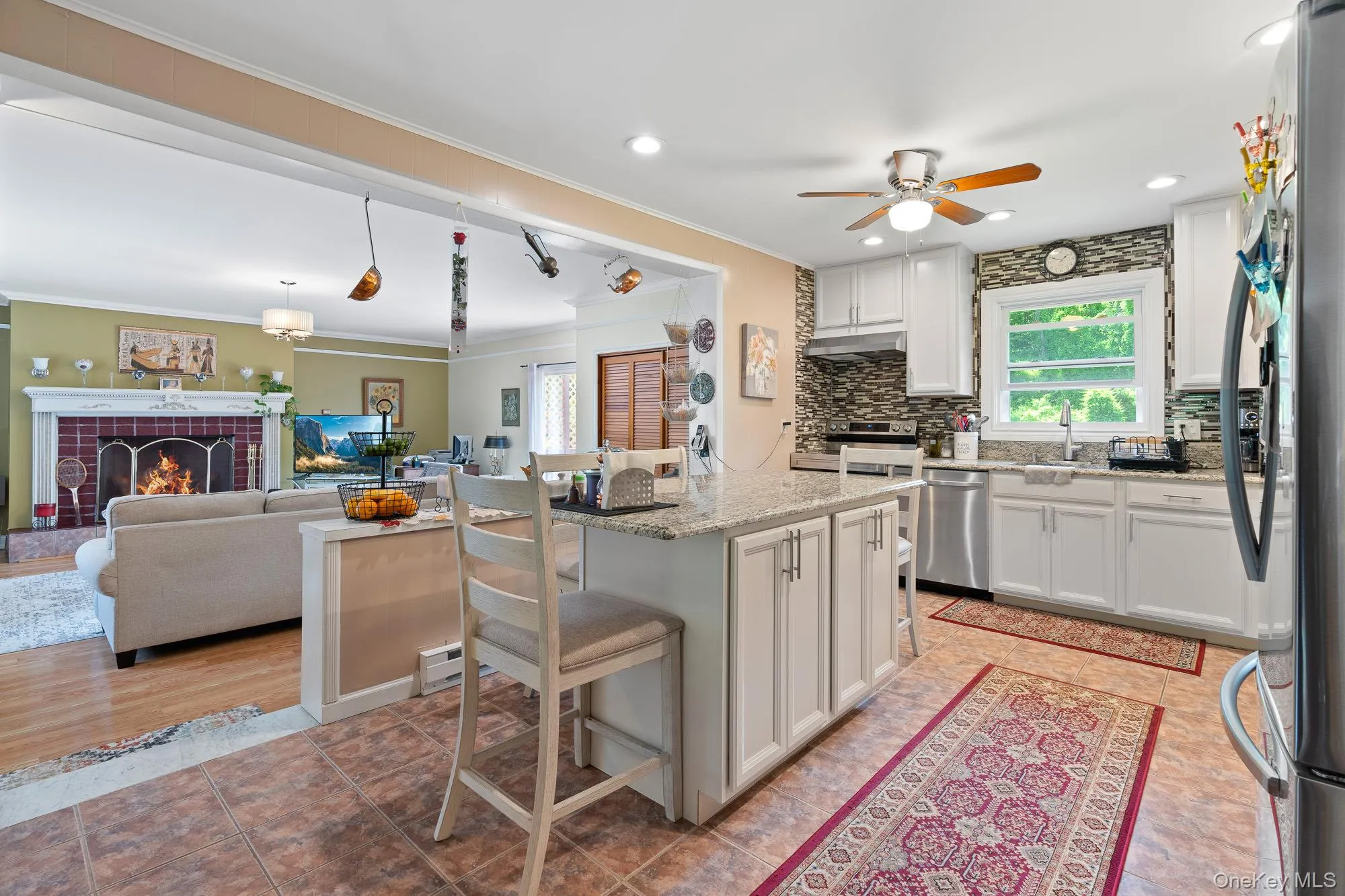Kitchen featuring stainless steel appliances, a kitchen breakfast bar, white cabinetry, a ceiling fan, and ornamental molding Kitchen featuring stainless steel appliances, a kitchen breakfast bar, white cabinetry, a ceiling fan, and ornamental molding