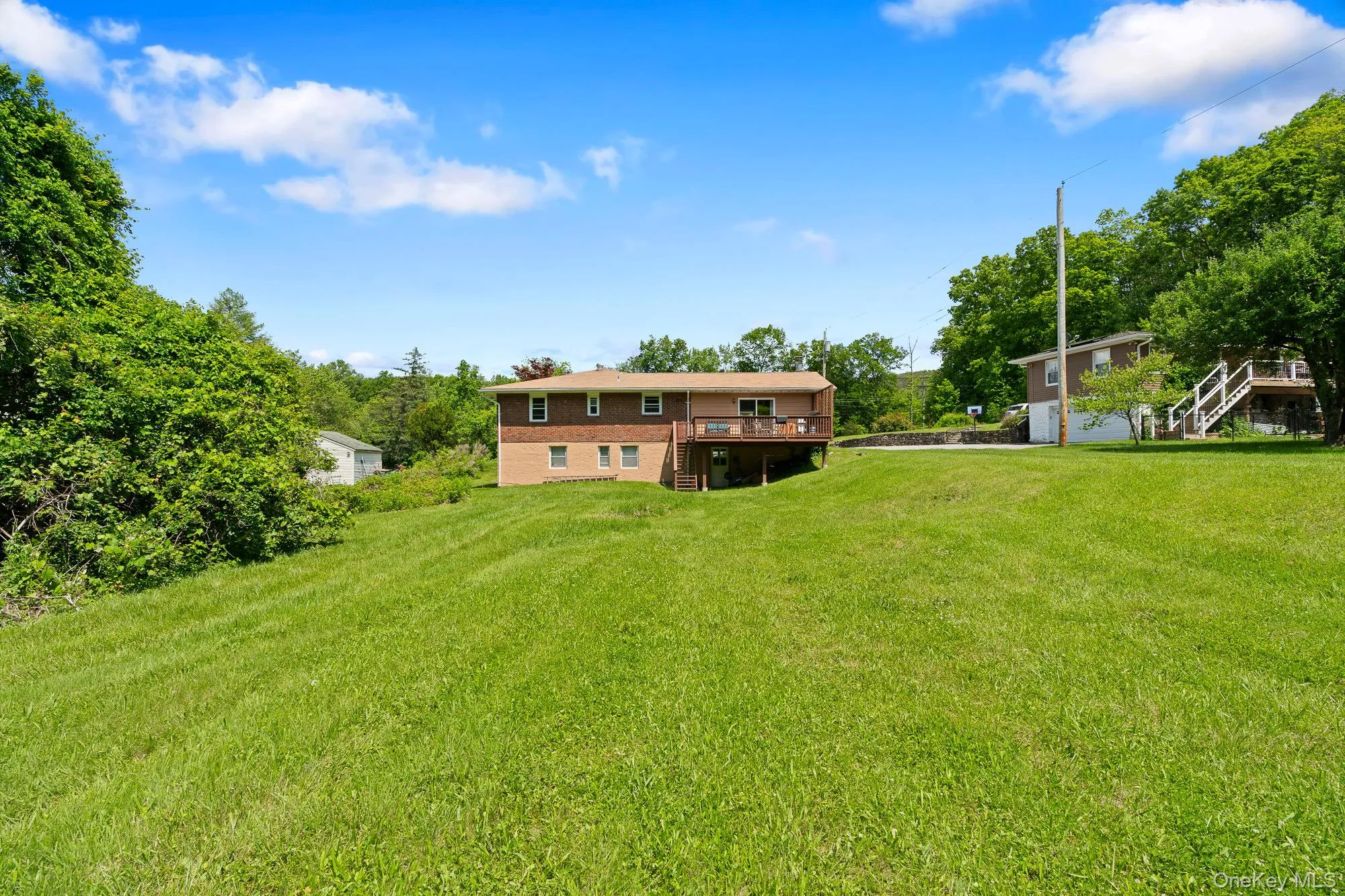 View of green lawn with stairway and a wooden deck View of green lawn with stairway and a wooden deck