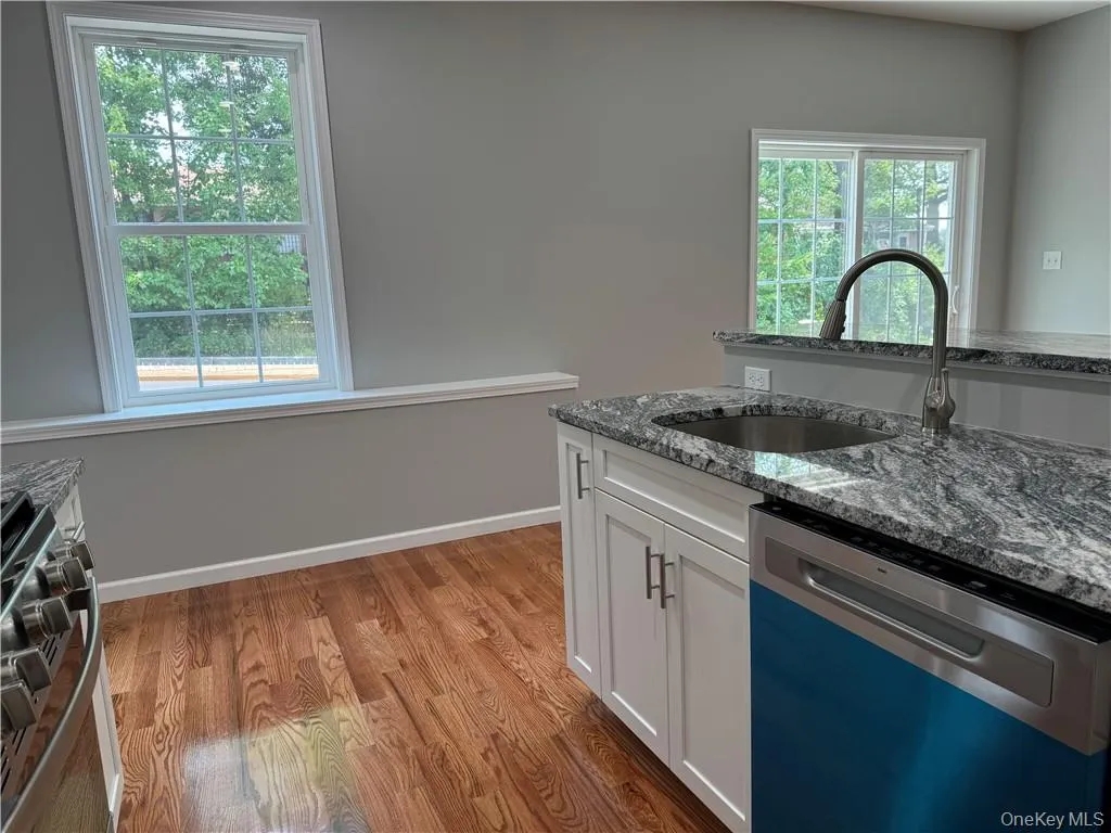 Kitchen featuring stone counters, white cabinets, sink, light hardwood / wood-style floors, and appliances with stainless steel finishes Kitchen featuring stone counters, white cabinets, sink, light hardwood / wood-style floors, and appliances with stainless steel finishes