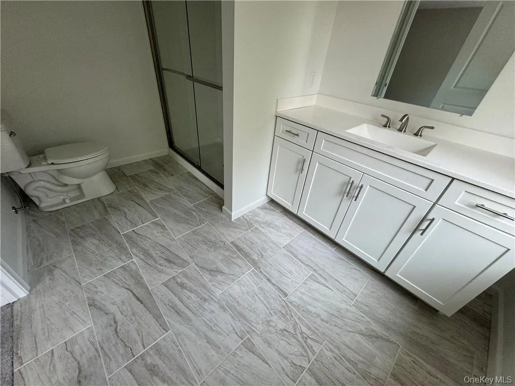 Bathroom with tile patterned flooring, a shower with shower door, toilet, and vanity Bathroom with tile patterned flooring, a shower with shower door, toilet, and vanity