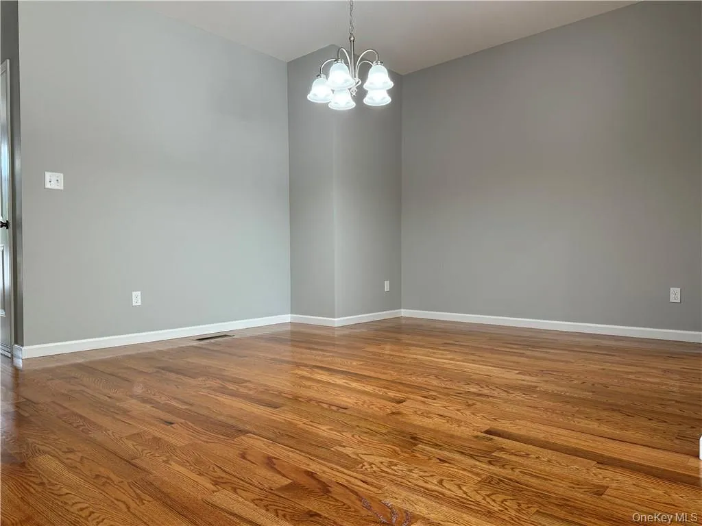 Empty room featuring hardwood / wood-style flooring and a chandelier Empty room featuring hardwood / wood-style flooring and a chandelier