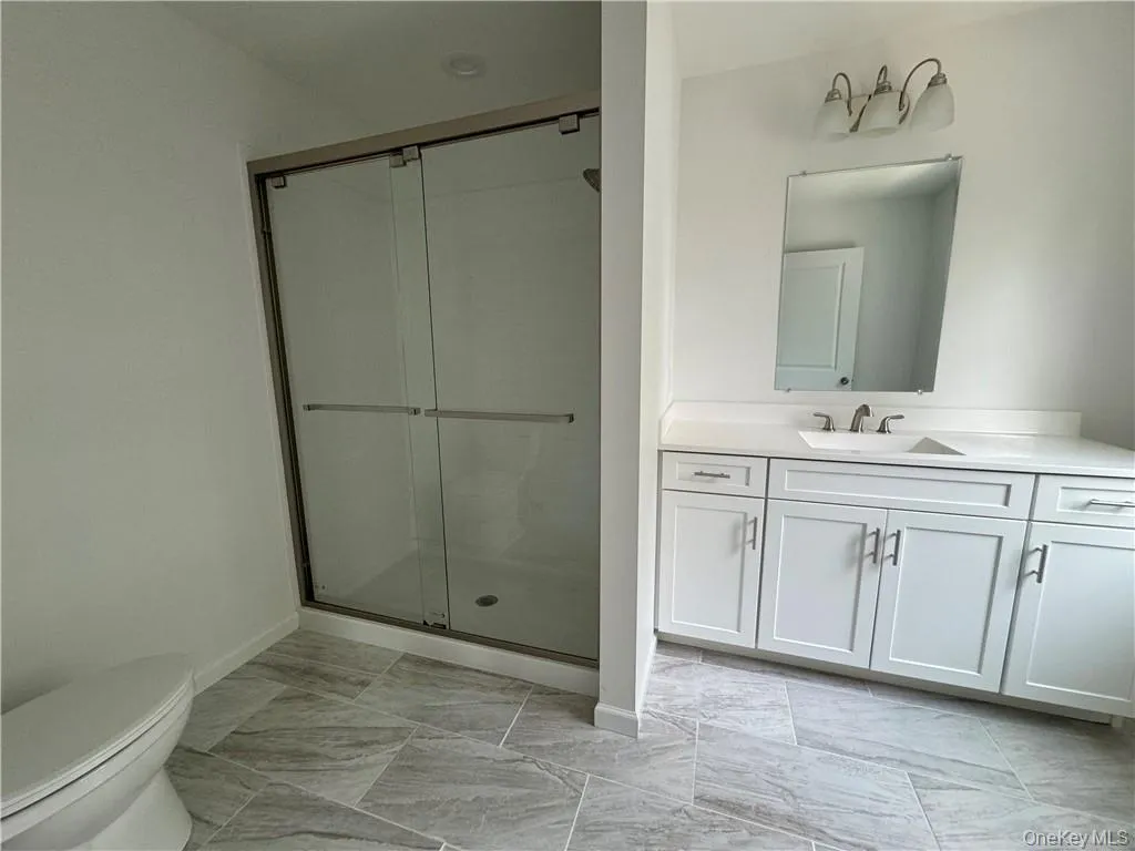 Bathroom featuring tile patterned flooring, walk in shower, toilet, and vanity Bathroom featuring tile patterned flooring, walk in shower, toilet, and vanity