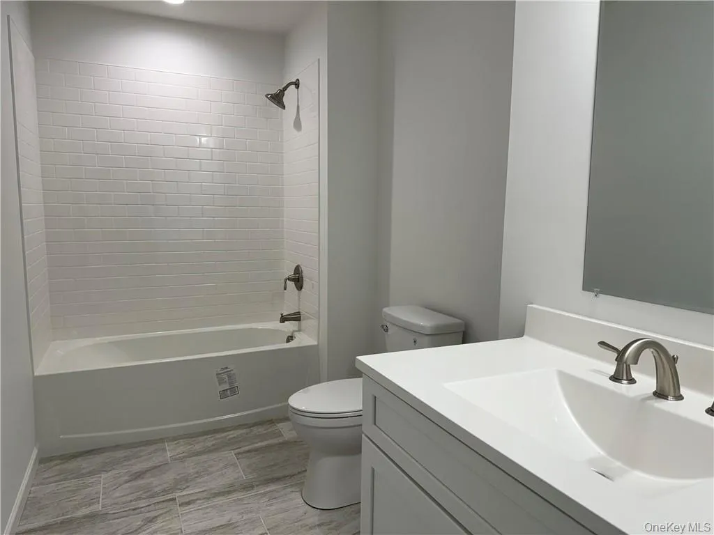 Full bathroom featuring tile patterned floors, toilet, vanity, and tiled shower / bath Full bathroom featuring tile patterned floors, toilet, vanity, and tiled shower / bath