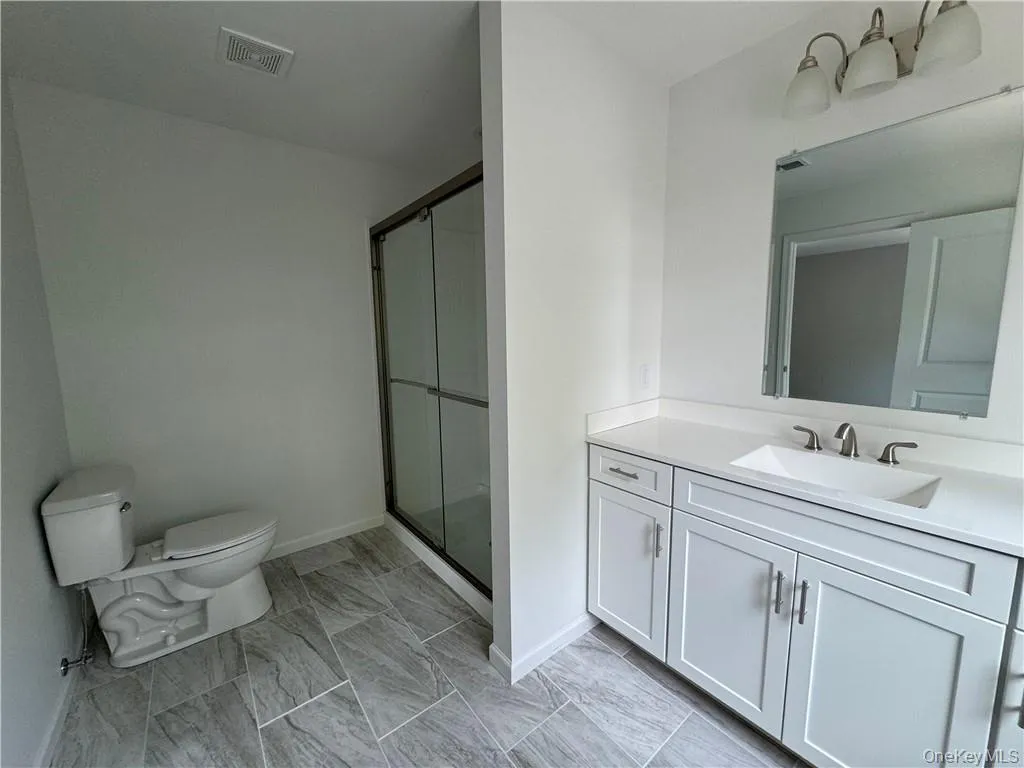 Bathroom featuring vanity, toilet, tile patterned floors, and walk in shower Bathroom featuring vanity, toilet, tile patterned floors, and walk in shower