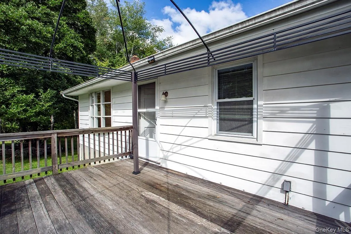 Wood-finish deck with railing, white siding, and an awning frame. Wood-finish deck with railing, white siding, and an awning frame.