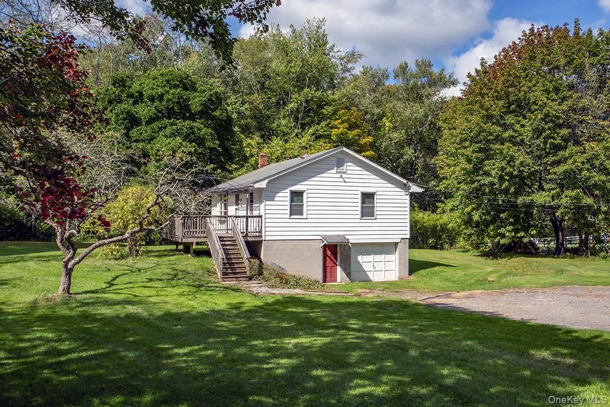 White siding exterior with a wood deck, wood stairs, and an attached garage White siding exterior with a wood deck, wood stairs, and an attached garage