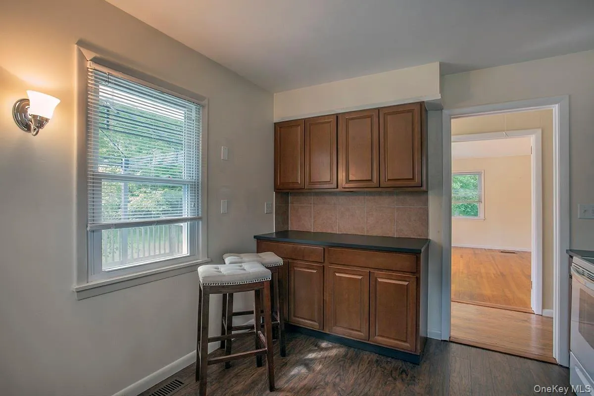 Built-in cabinetry with dark countertops, tiled backsplash, and wood-finish flooring Built-in cabinetry with dark countertops, tiled backsplash, and wood-finish flooring