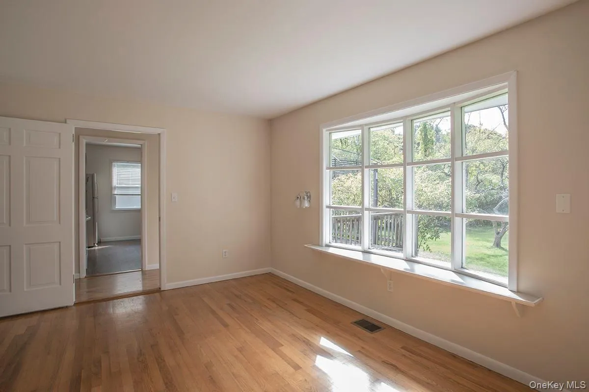 Hardwood flooring, painted interior walls, bay window with sill, white interior doors, and a partial outdoor landscape Hardwood flooring, painted interior walls, bay window with sill, white interior doors, and a partial outdoor landscape