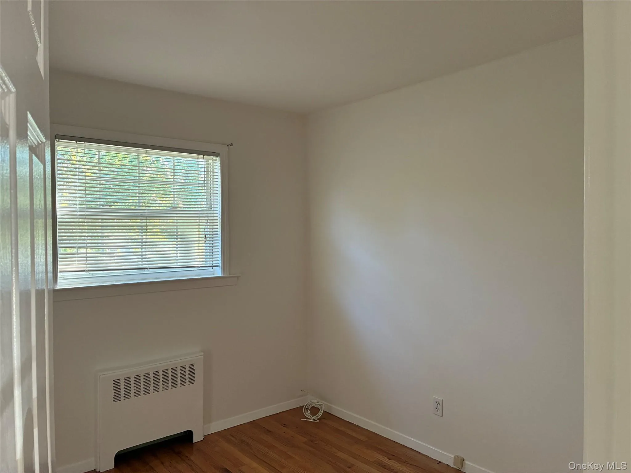 Hardwood-style flooring and a window with blinds Hardwood-style flooring and a window with blinds