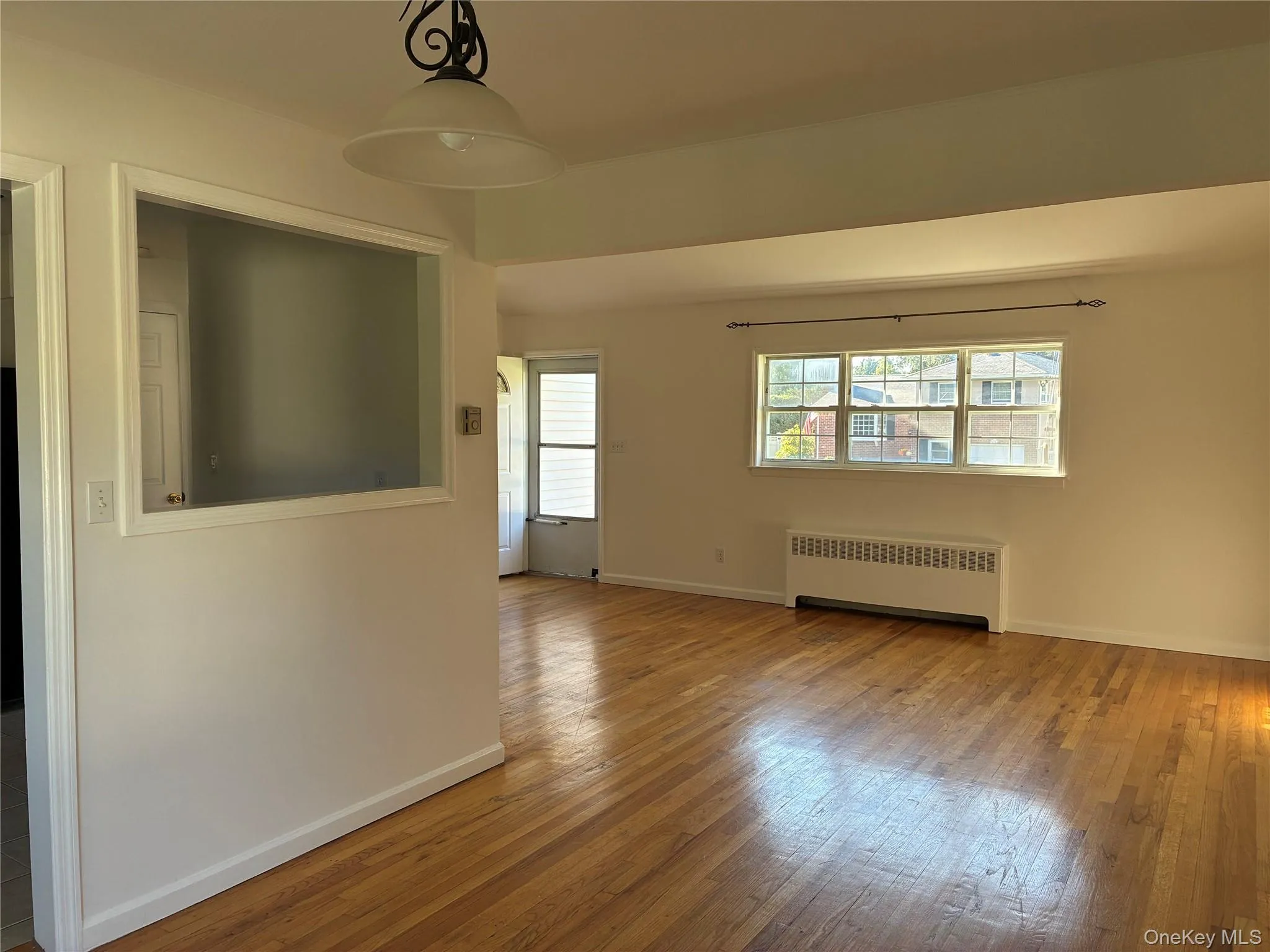 Hardwood flooring, painted white walls, white trim, and a built-in radiator Hardwood flooring, painted white walls, white trim, and a built-in radiator