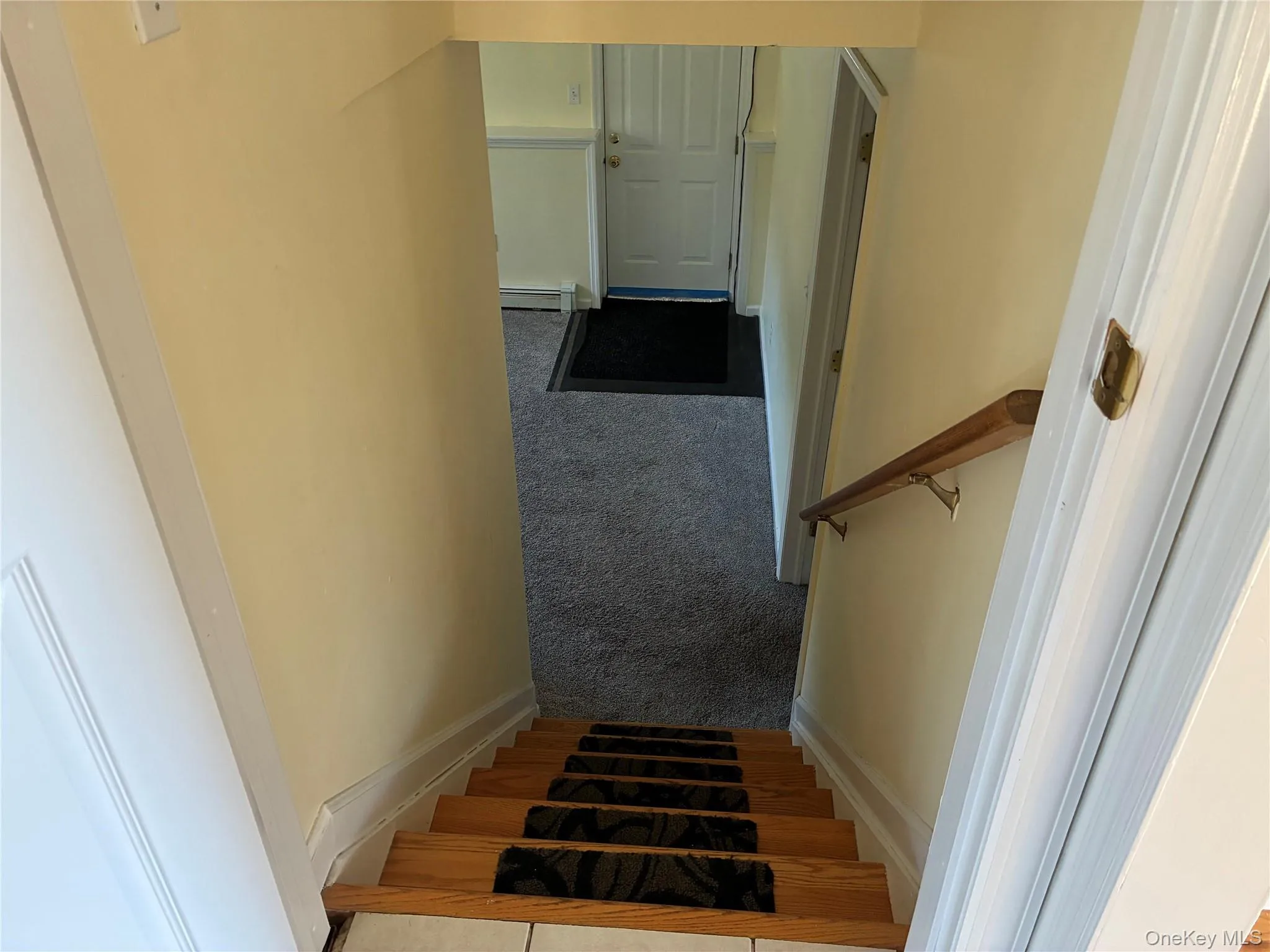 Stairs to den. Wood-finish stairs with risers, a light-colored wall, and a wooden handrail Stairs to den. Wood-finish stairs with risers, a light-colored wall, and a wooden handrail