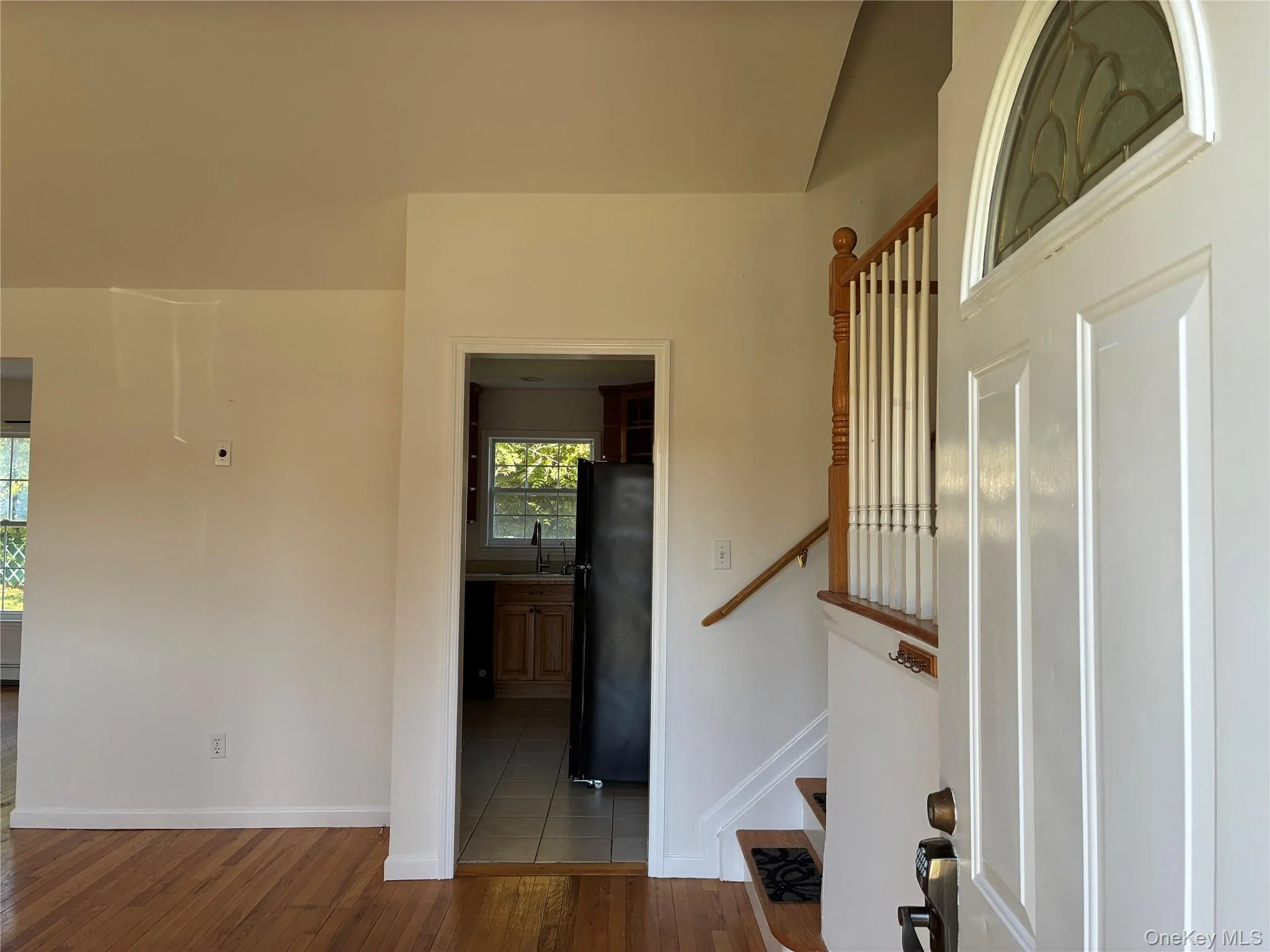 Entryway with a wood-finish staircase with white balusters, and wood-finish flooring Entryway with a wood-finish staircase with white balusters, and wood-finish flooring