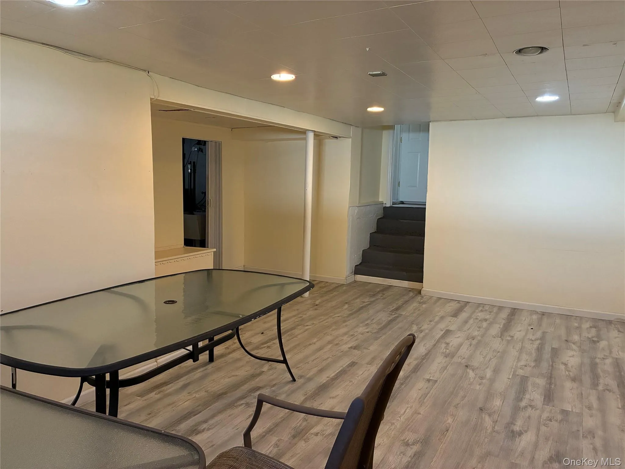 Finished room featuring wood-finish flooring, recessed lighting, and a partial wall separating spaces Finished room featuring wood-finish flooring, recessed lighting, and a partial wall separating spaces