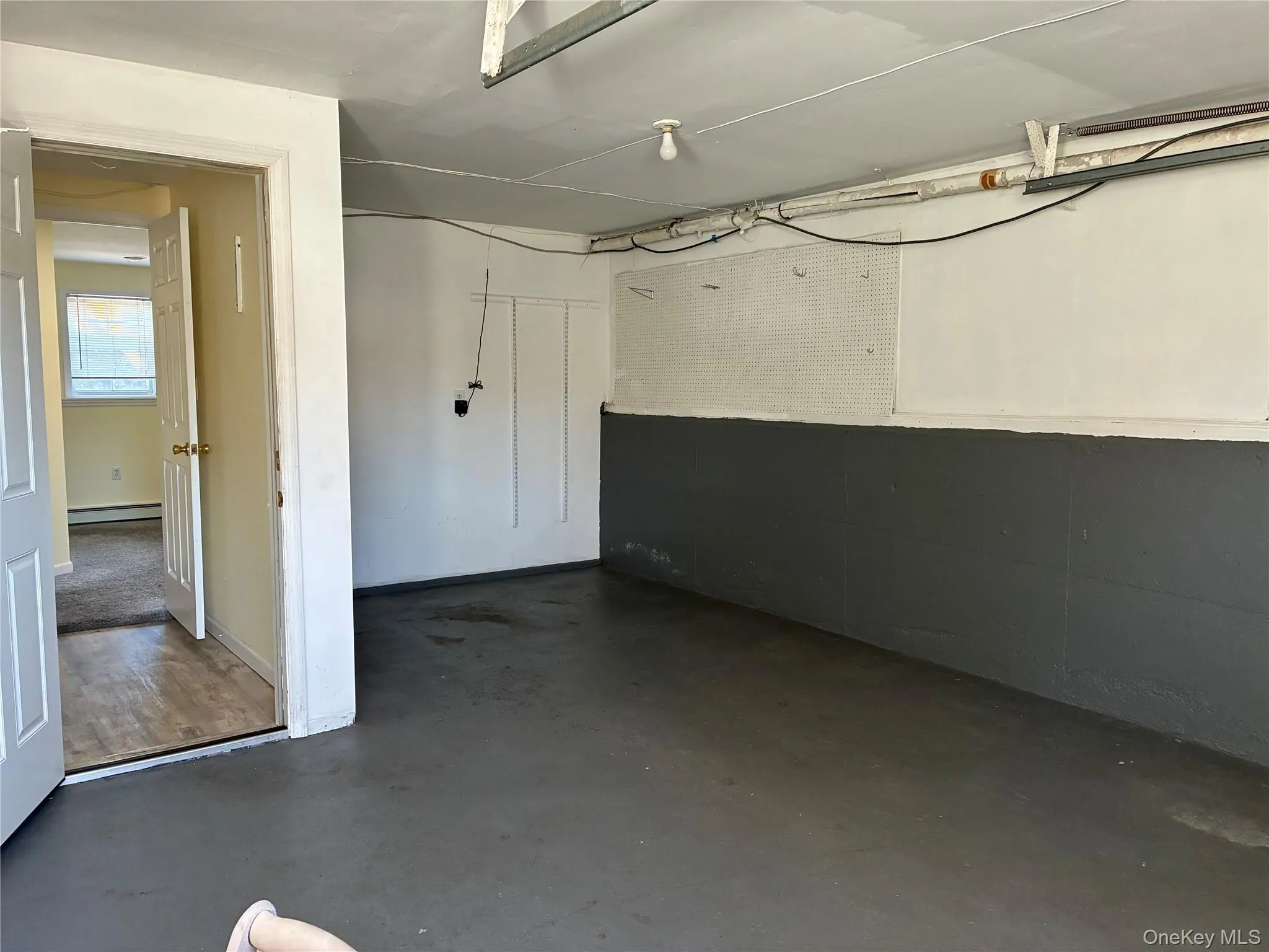 Attached garage with painted concrete flooring and exposed ceiling utilities Attached garage with painted concrete flooring and exposed ceiling utilities