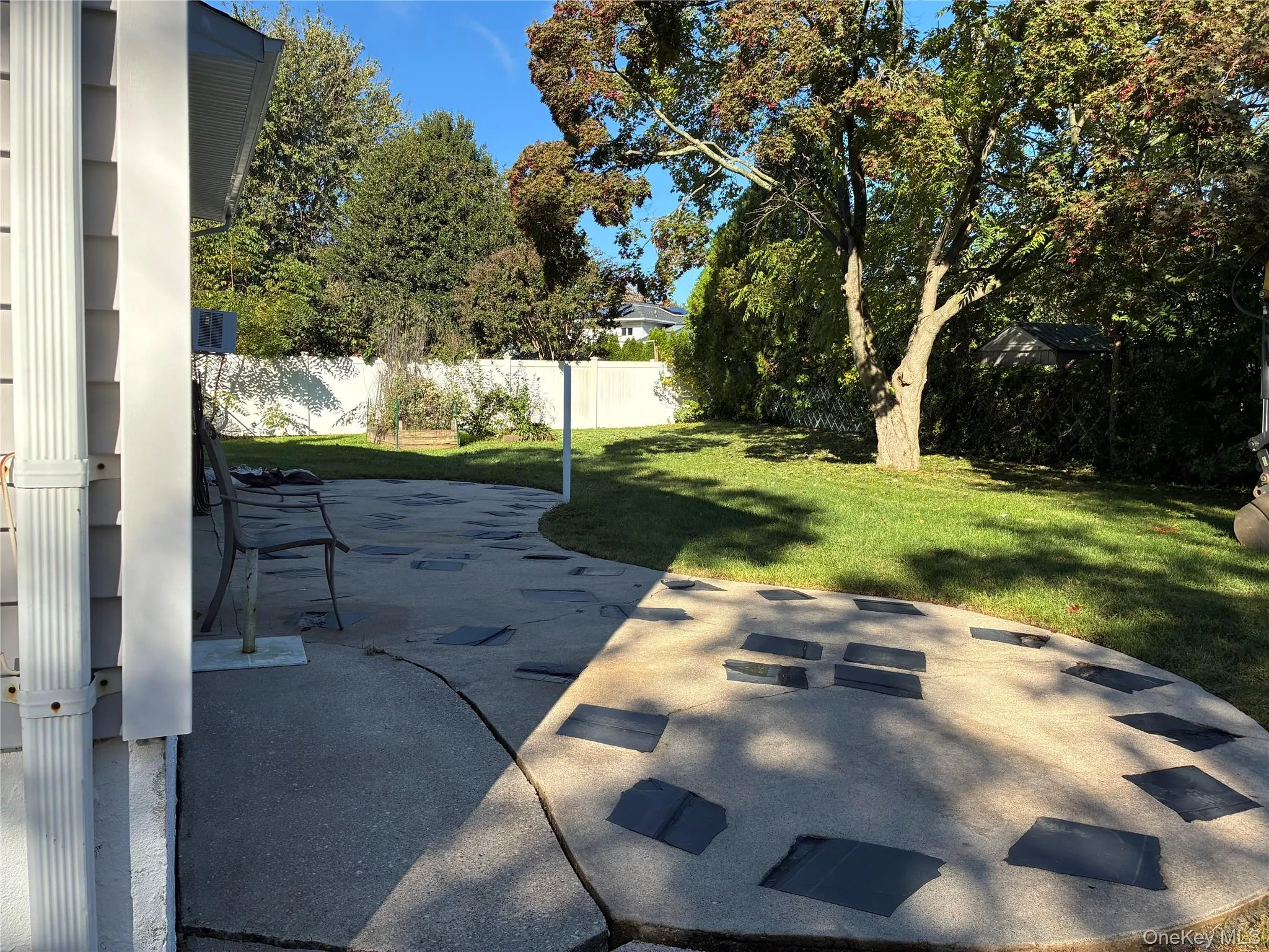 Expansive backyard featuring a manicured lawn, mature trees, a privacy fence, and a concrete patio with decorative inserts Expansive backyard featuring a manicured lawn, mature trees, a privacy fence, and a concrete patio with decorative inserts
