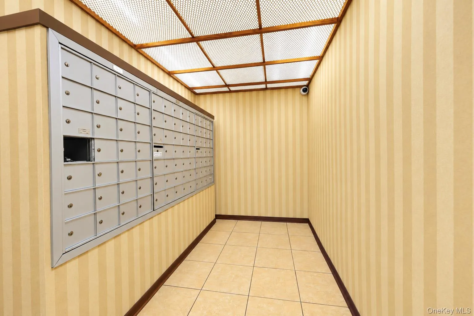Mail room featuring a large bank of individual mailboxes, tile flooring, and striped wall coverings Mail room featuring a large bank of individual mailboxes, tile flooring, and striped wall coverings