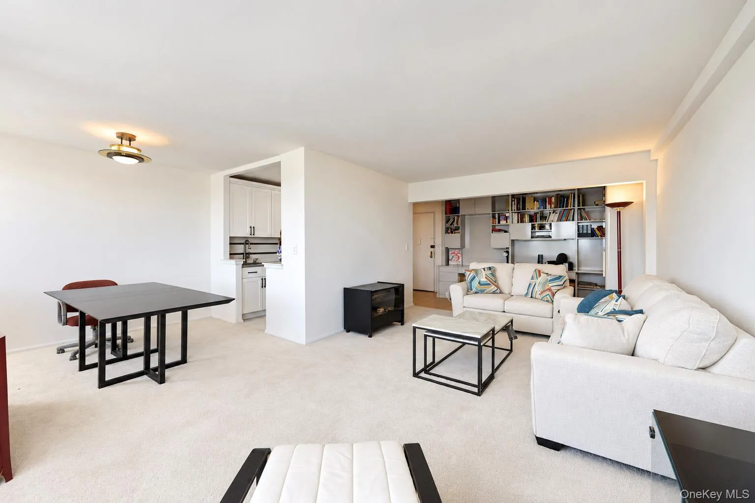 Open-concept living area featuring a kitchen pass-through, recessed lighting, and integrated shelving Open-concept living area featuring a kitchen pass-through, recessed lighting, and integrated shelving