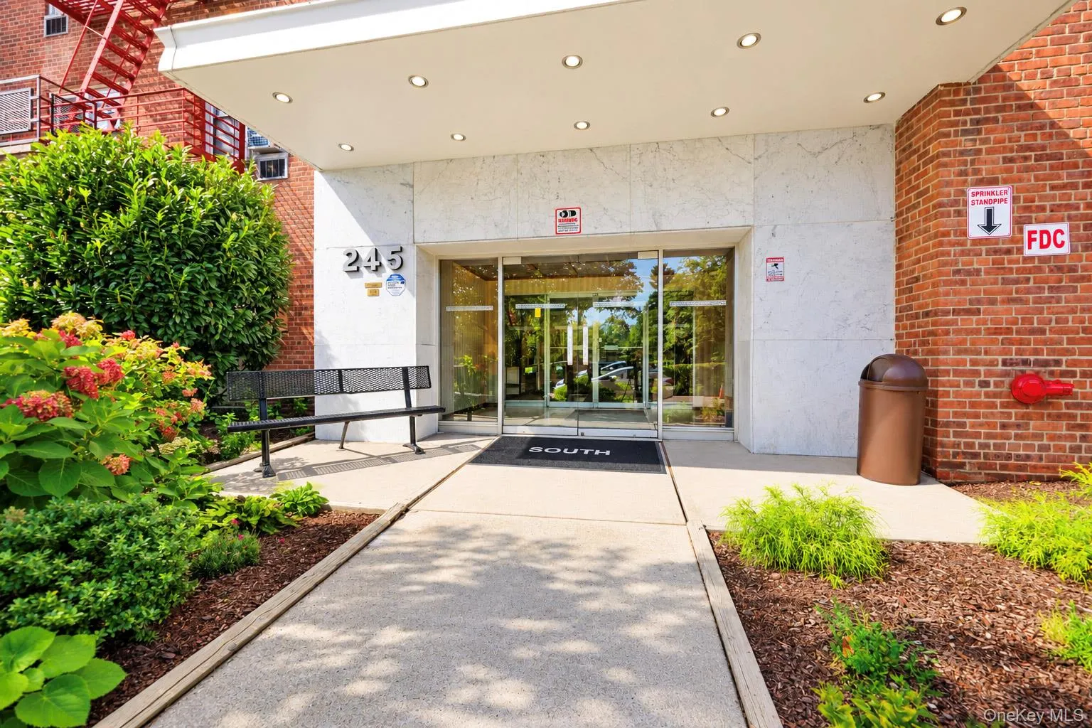 Brick and stone-clad exterior with a concrete pathway leading to a glass entry door Brick and stone-clad exterior with a concrete pathway leading to a glass entry door