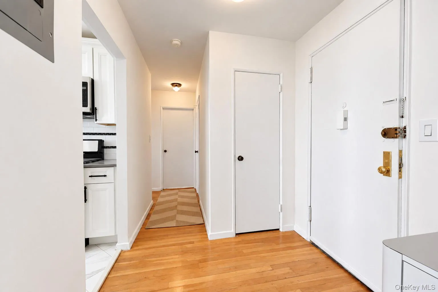 Hardwood flooring, recessed lighting, white cabinetry, integrated microwave, and a tiled backsplash Hardwood flooring, recessed lighting, white cabinetry, integrated microwave, and a tiled backsplash